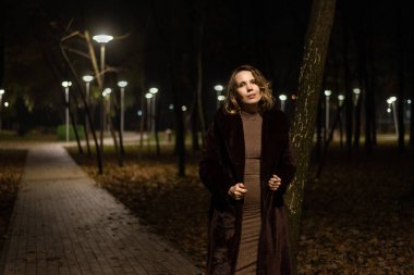 Gece fenerlerle aydınlatılmış bir parkta kürklü bir kadın..