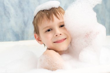 Sabunlu köpüklü bir çocuk banyoda yıkanıyor. Hijyen, temizlik konsepti.