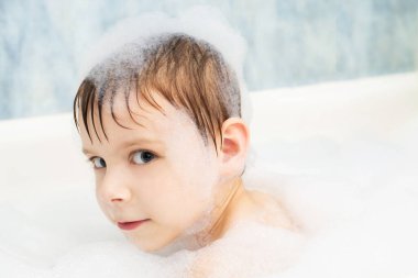 Sabunlu köpüklü bir çocuk banyoda yıkanıyor. Hijyen, temizlik konsepti.