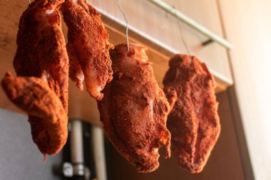 Baharatlandırılmış et parçaları kancalarda asılı. Kurutulmuş tavuk eti, kurutulmuş et..