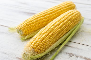 Beyaz ahşap arka planda tam mısır. Vejetaryen yemeği..