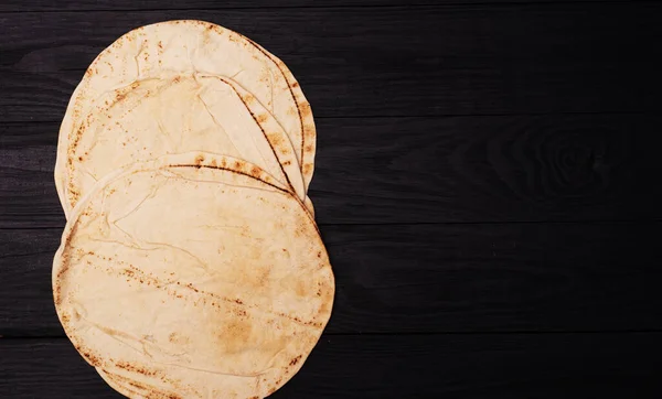 濃い木目の背景に丸いピタパン — ストック写真