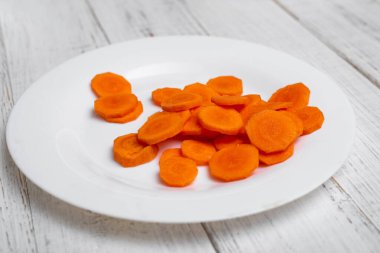 Tabakta dilimlenmiş havuç. Beyaz ahşap arka planda.