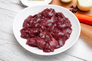 Tabakta çiğ tavuk ciğeri. Beyaz ahşap arka planda.