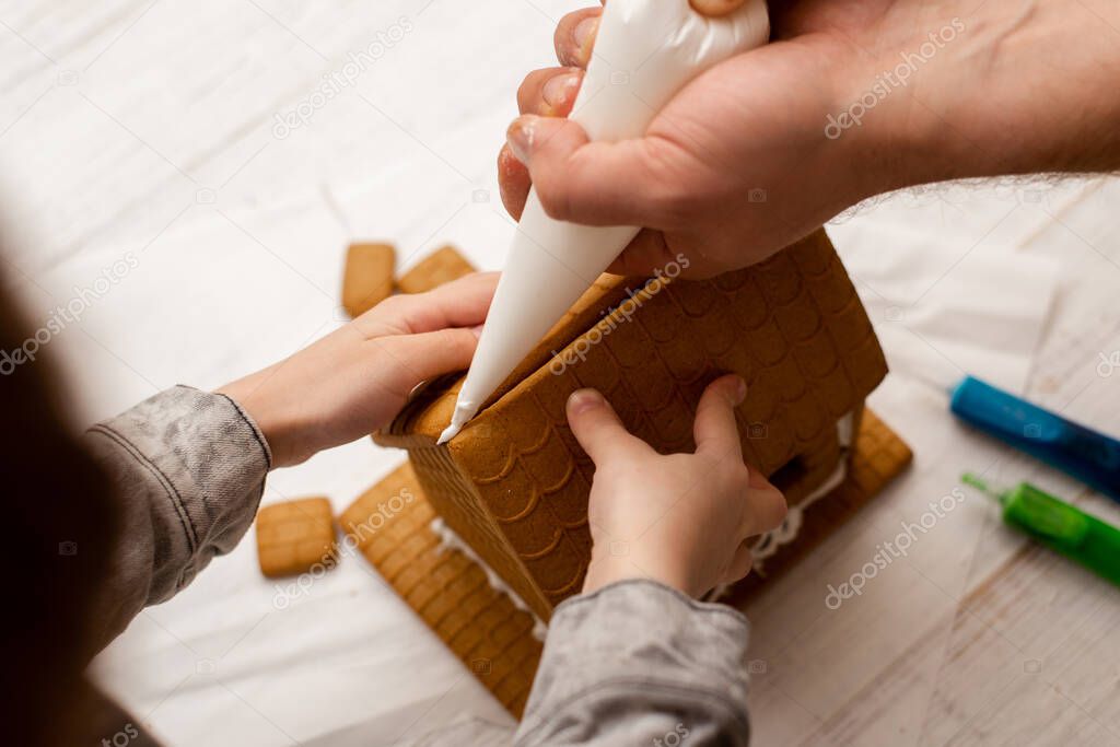 Dad and son are making a gingerbread house. Preparing for Christmas.