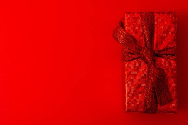 Kırmızı arka planda kırmızı bir paket hediye. Noel, Sevgililer Günü hediyesi.