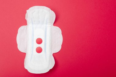 Kırmızı arka planda dişi pedi. Regl için hijyen ürünü.