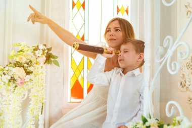 Teleskoplu bir çocuk ve annesi merdivenlerde oturuyor. Kadın çocuğa yolu gösterir..