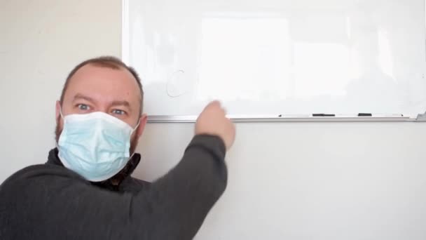 Läraren Orakad Man Medicinsk Mask Förklarar Raskt Nära Vit Tavla — Stockvideo