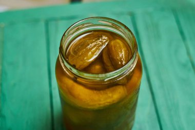 Yeşil arka planda kavanozda salatalık turşusu..