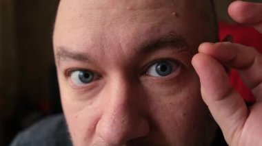 Adam parmaklarıyla kaşındaki saçı yoluyor..