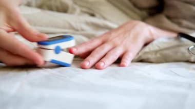 Kadın yatakta parmağına oksitölçer takıyor..