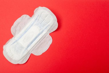 Kırmızı arka planda dişi pedi. Regl için hijyen ürünü.