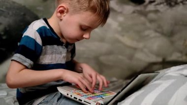 Genç okul çocuğu dizüstü bilgisayarda çalışıyor. Oğlan yazı yazıyor. Uzaklık öğrenimi, ev eğitimi.