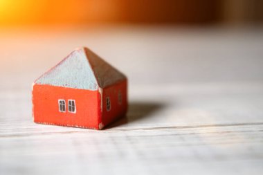 Hafif arka planda tahta bir oyuncak ev. Emlak, inşaat, kiralık konut kavramı.