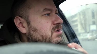 Şoför gergin bir şekilde arabada sigara içiyor. Yorgunluk, gerginlik..