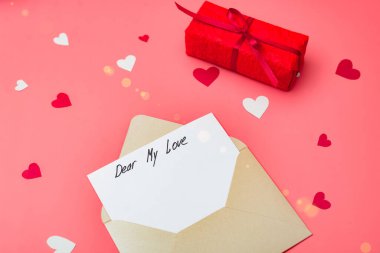 Sevgili aşkım, mektubun başlangıcının metni. Kırmızı arka planda kalpleri olan bir zarf. Sevgililer Günü için ilan-ı aşk.