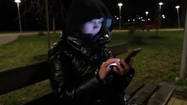 Geceleri bir kadın telefonda parkta bir bankta yazıyor..