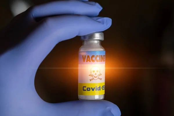 Tehlike, aşı koronavirüs konsepti korkusu. Eldivenli ellerde toksik madde uyarısı olan aşı etiketi.