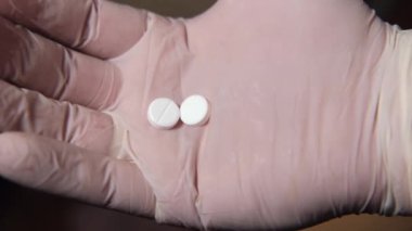 Eldivenli eldeki iki hap yere düştü..