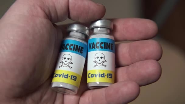コロナウイルスの概念による予防接種の危険性 男性の手にラベルに危険標識が付いているワクチン — ストック動画