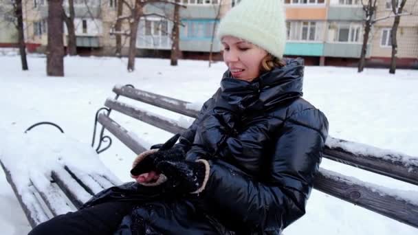女性が雪に覆われたベンチに座っている — ストック動画