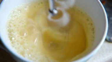Karıştırıcı yumurtaları yakın plan köpükle karıştırıyor. Omlet pişiriyorum..