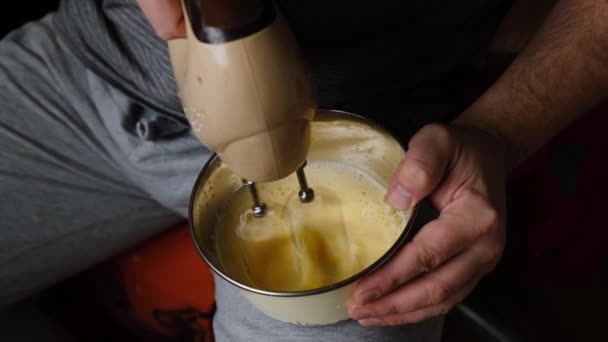 Man Slår Ägg Med Mixer Som Håller Skål Mellan Benen — Stockvideo