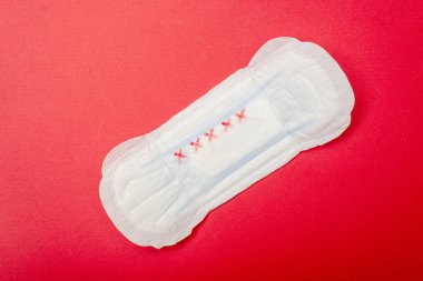 Kırmızı arka planda dişi pedi. Regl için hijyen ürünü.