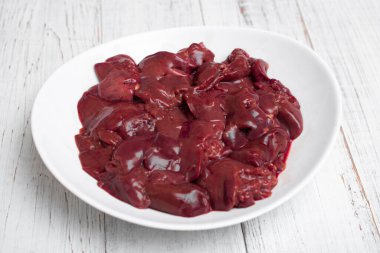 Tabakta çiğ tavuk ciğeri. Beyaz ahşap arka planda.