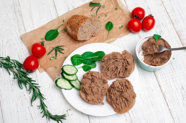 Sandviç, tavuk etli kanepe, domates ve salatalık. Beyaz ahşap arka planda.