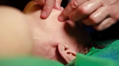 Yüz masajı yakın çekim. Masör, kadın yüzüne parmaklarıyla masaj yapar..