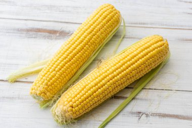 Beyaz ahşap arka planda tam mısır. Vejetaryen yemeği..