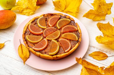 Beyaz ahşap arka planda balkabağı turtası. Sarı sonbahar yaprakları, elmalar ve armutlar.