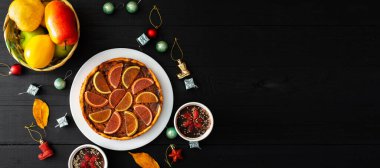 Balkabağı turtası, tatlı tatlılar ve siyah arka planda Noel oyuncakları. Metin için yer.