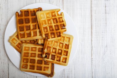 Taze pişmiş Belçika waffle 'ı beyaz bir tabakta, ahşap bir arka planda..