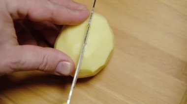 Bıçak, çiğ patatesleri kesme tahtasına yakın plan kesiyor..