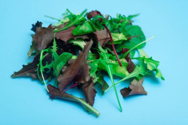 Mavi arka planda çeşitli taze salata sebzeleri. Sağlıklı, vejetaryen yiyecekler, çiğ gıda konsepti.