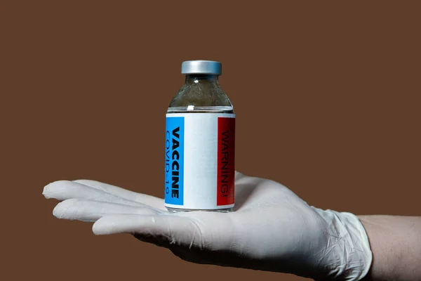 No vaccination for coronavirus. Vaccine side effects hazard concept. A hand holds a warning vial on the back.