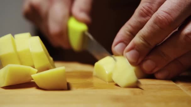 Ein Mann Schneidet Rohe Kartoffeln Auf Einem Schneidebrett — Stockvideo