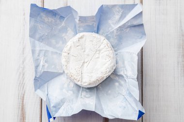 Beyaz ahşap arka planda kağıt üzerinde yuvarlak mavi peynir..