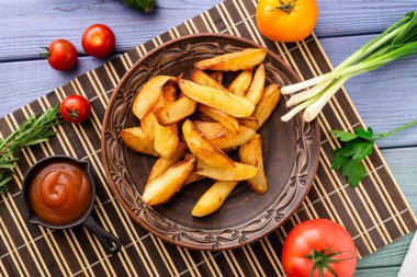 Masadaki tabakta farklı sebzelerle birlikte büyük parçalar halinde kızarmış patates..