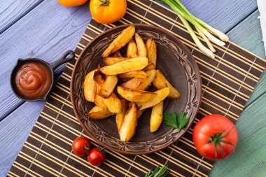 Masadaki tabakta farklı sebzelerle birlikte büyük parçalar halinde kızarmış patates..