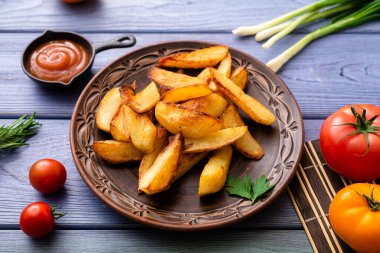 Masadaki tabakta farklı sebzelerle birlikte büyük parçalar halinde kızarmış patates..