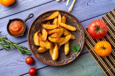 Masadaki tabakta farklı sebzelerle birlikte büyük parçalar halinde kızarmış patates..