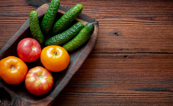 Свежие огурцы и помидоры на деревянном фоне.