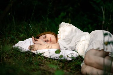 Sağlıklı bir uyku. Dinlen, ormanda rahatla. Ormandaki yeşil bir arazide bir yastıkta uyuyan bir kadın..