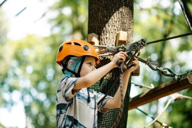 İp parkındaki genç çocuk. Çocuğun geri kalanı parkta dinleniyor..