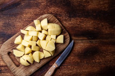 Ahşap zeminde dilimlenmiş çiğ patates. Yemek hazırlığı.