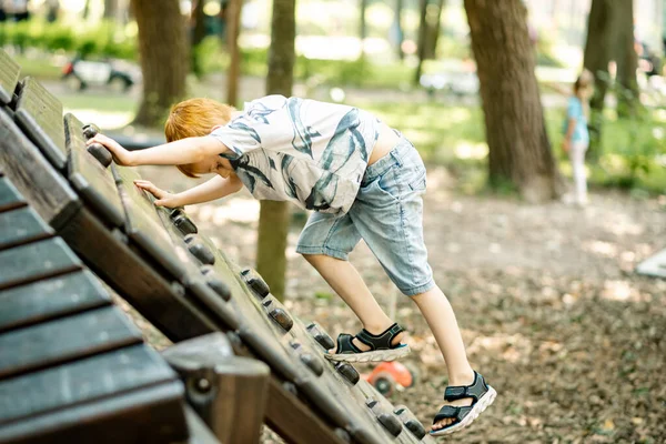 Ein Kleiner Junge Klettert Auf Einer Holzrutsche Auf Dem Spielplatz — Stockfoto